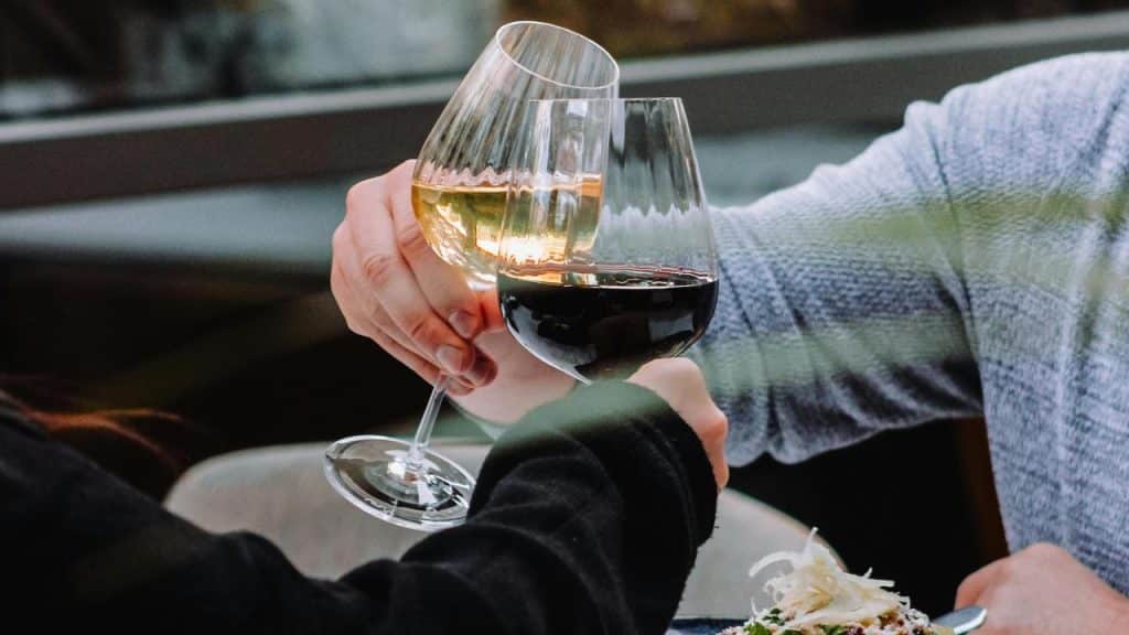 A close-up of two people clinking glasses of wine.