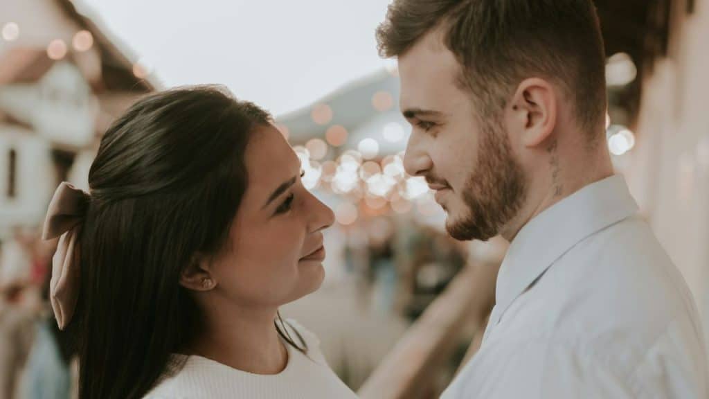 A woman with a bow in her hair looks up at a man in a white shirt.