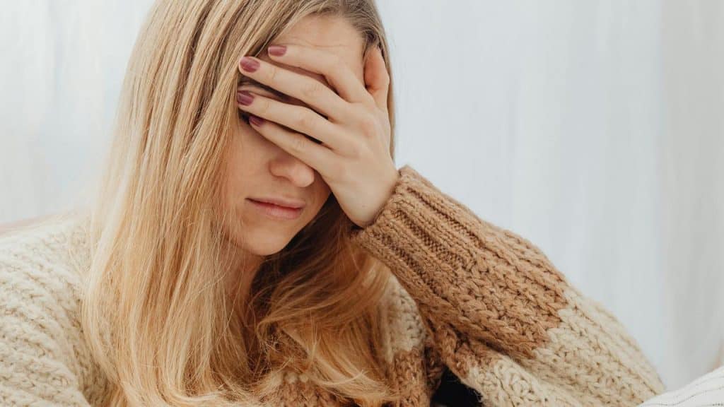 A woman covering her face with her hand in distress.