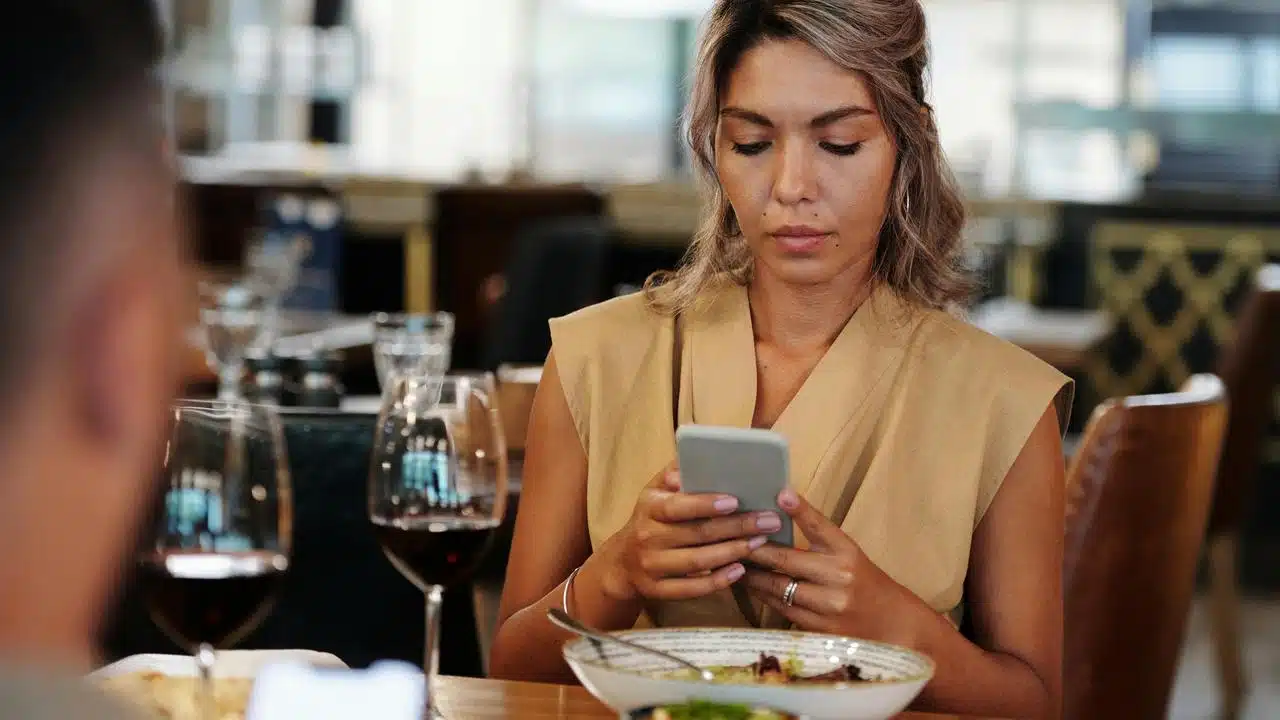 A woman looking at her phone while sitting at a restaurant table.