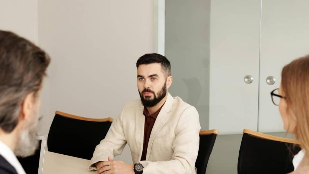 A person seated at a table during a business meeting with two others.