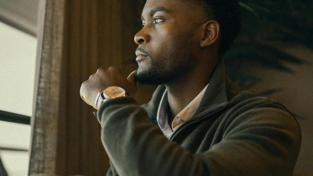 A man resting his chin on his hand and looking thoughtfully out a window.