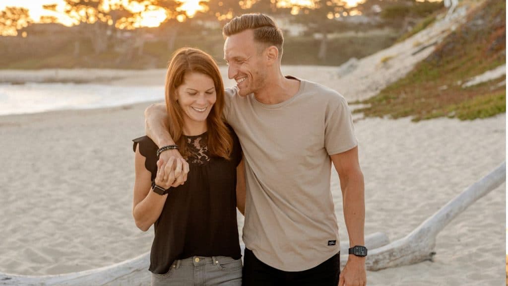 A man and a woman walking through a beach during daytime.