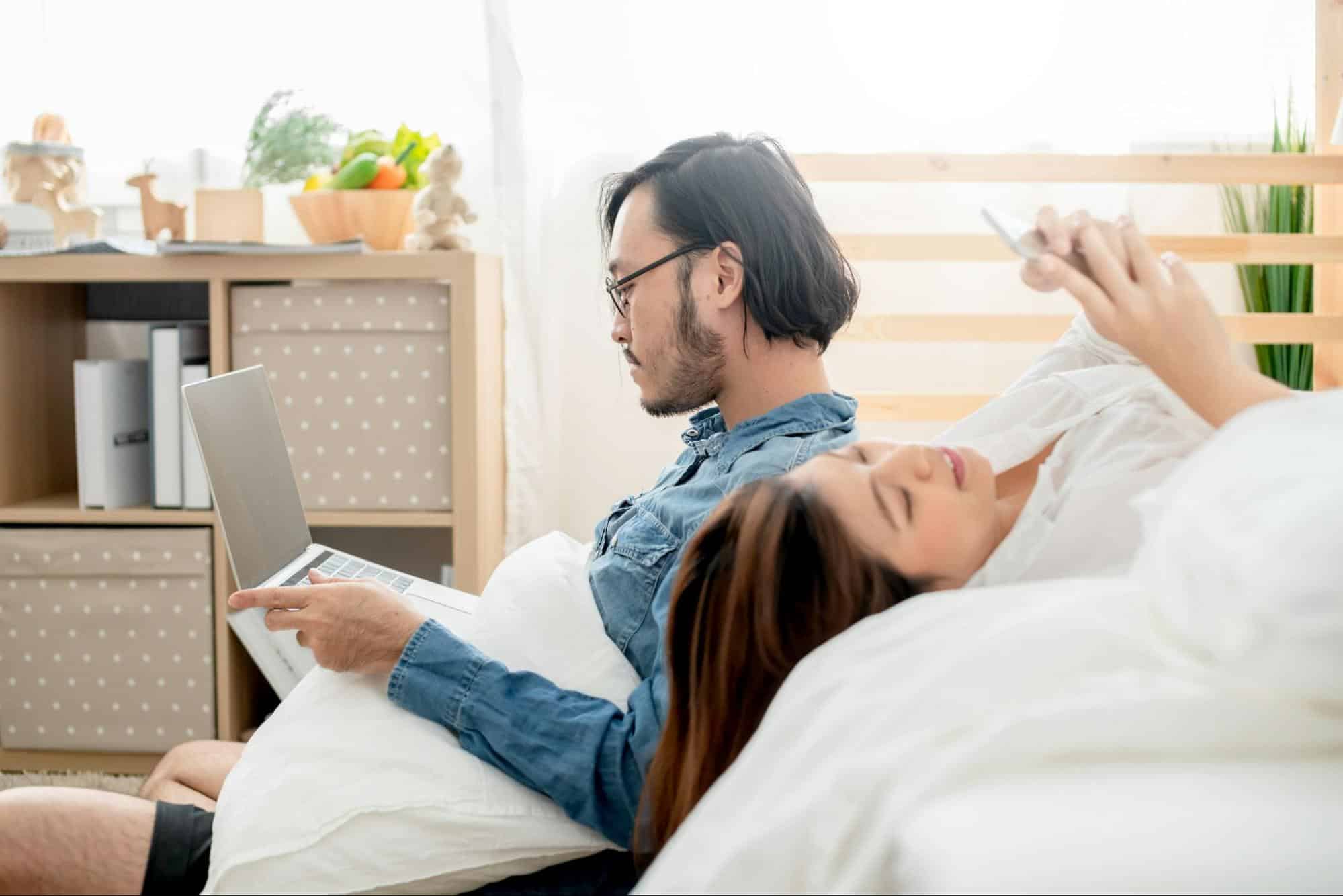A man and woman ignoring each other because of gadgets