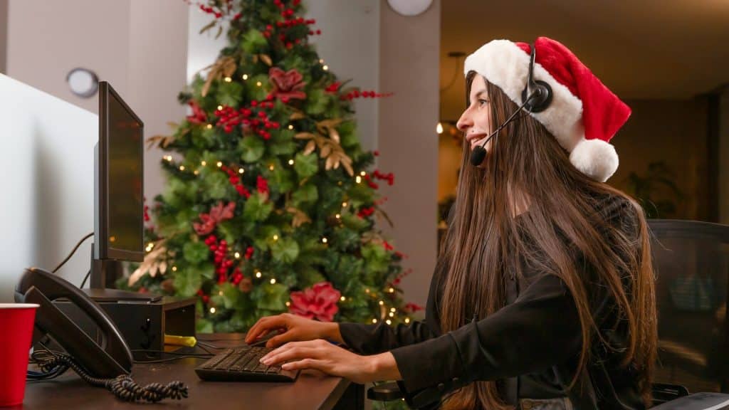 A woman wearing a Santa hat using a computer.