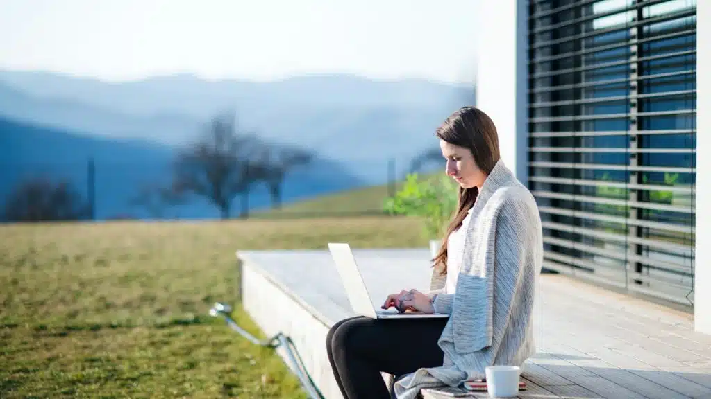 A woman working on a laptop while sitting on the lawn.