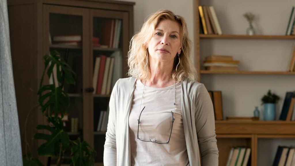 An elegant woman in grey casual wear standing in the middle of the living room.
