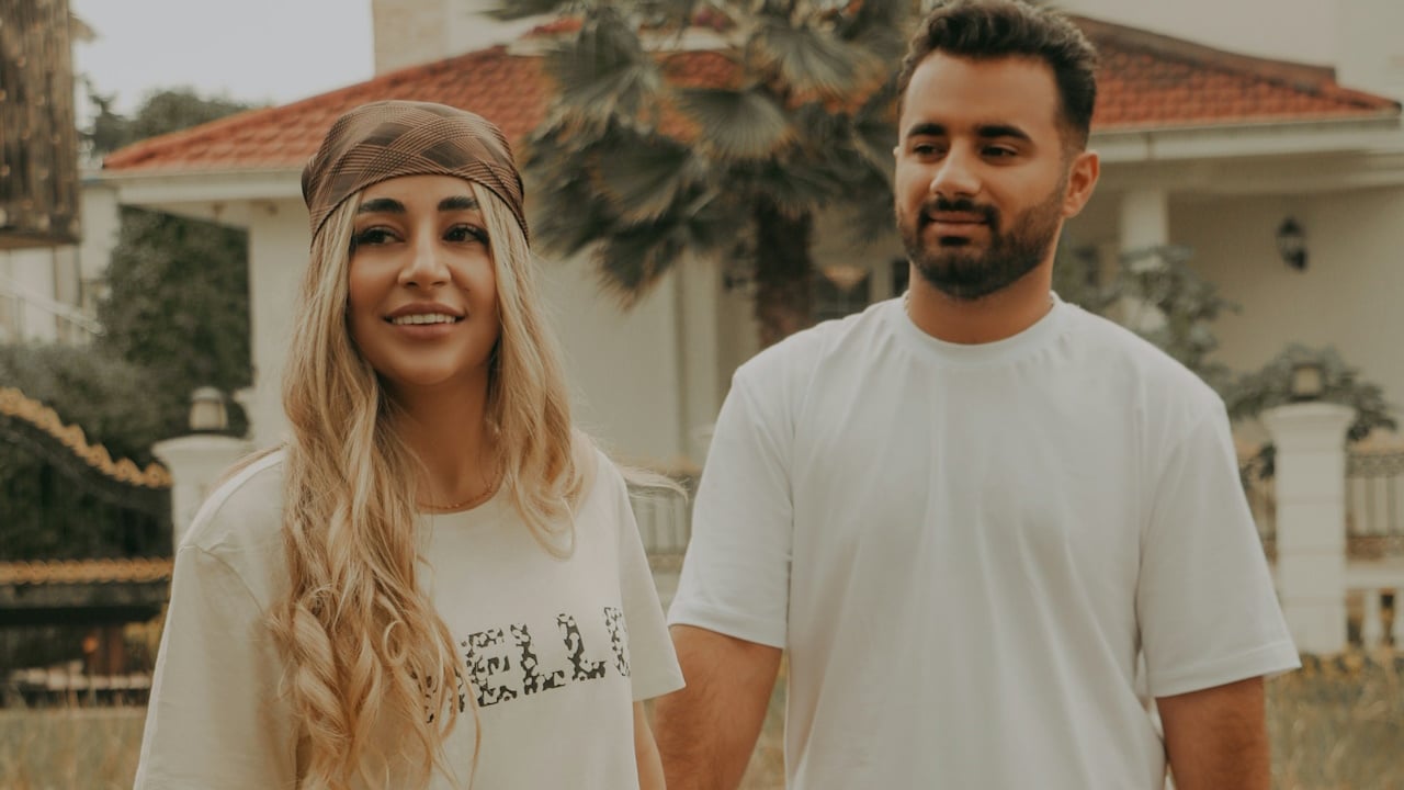 A man and a woman standing in front of a house.