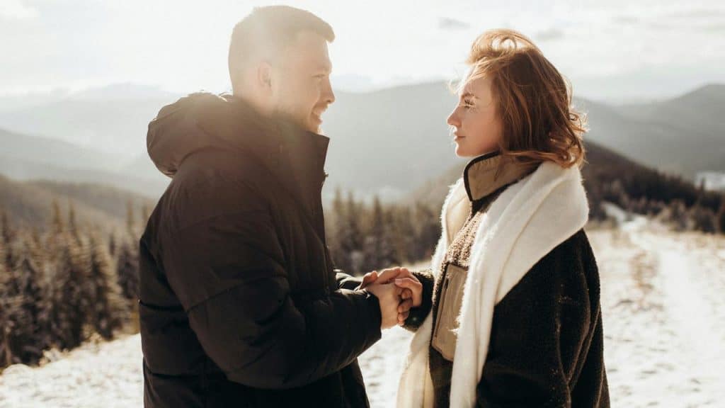 A couple holding hands in a snowy mountain landscape.