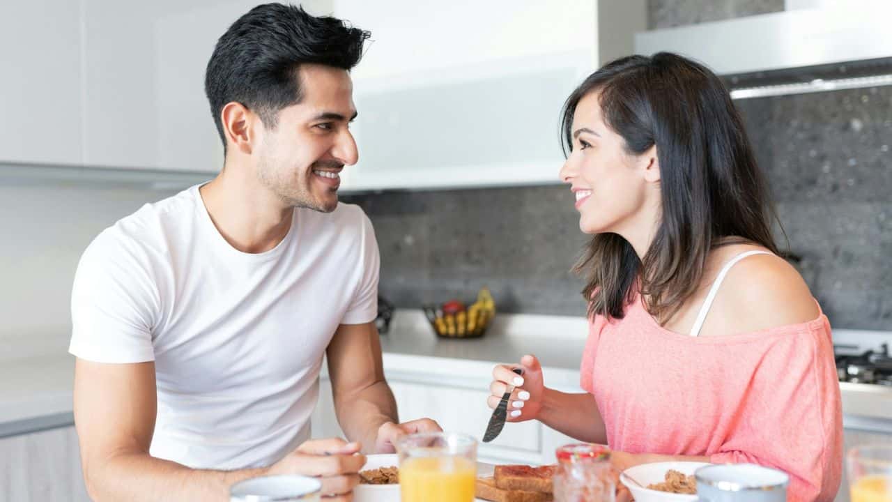 Smiling couple having breakfast together and looking at each other across the table.