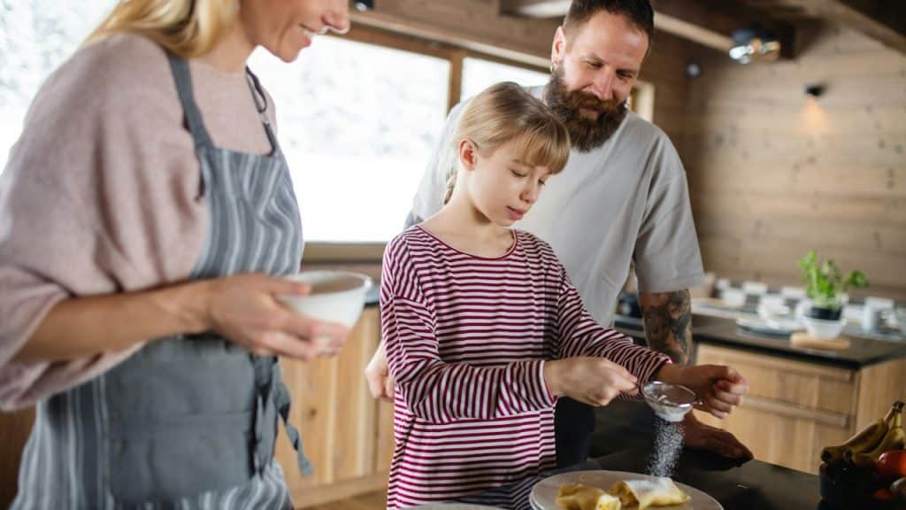 A happy family with a small daughter cooking indoors during a winter holiday in a private apartment.
