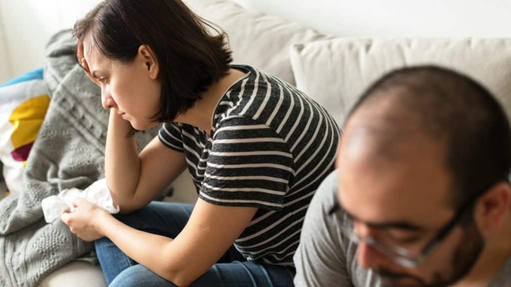 An unhappy couple sitting quietly on the couch.
