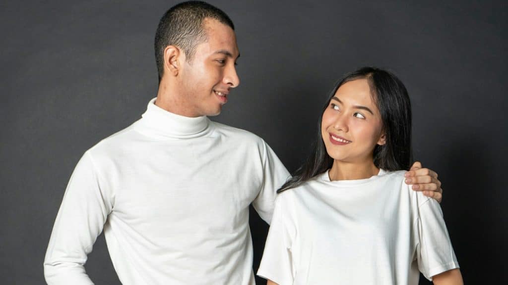 A man with his arm resting on a woman’s shoulder as they both smile at each other.
