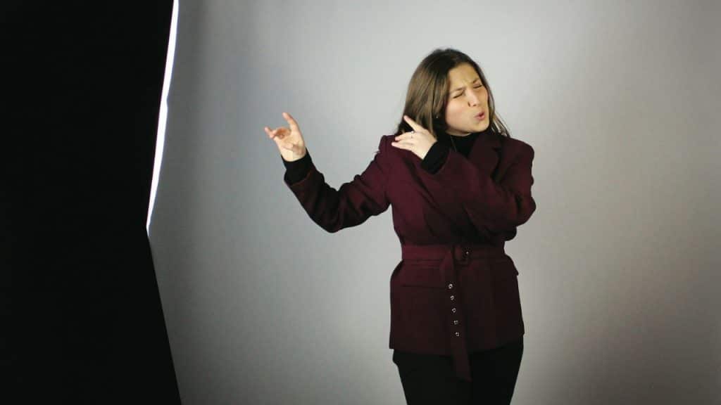 A woman in a magenta jacket strikes a pose against a studio background.