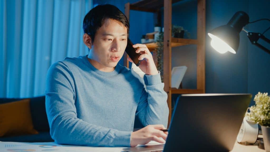 A businessman calling on his cellphone while working on a laptop.
