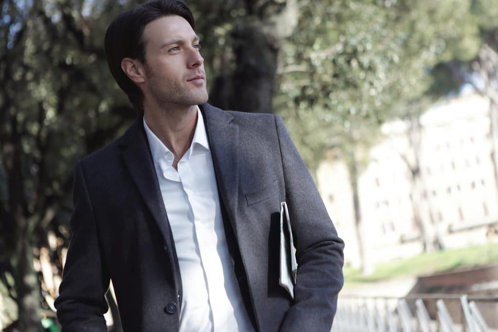 A man in a black suit looking at the side.