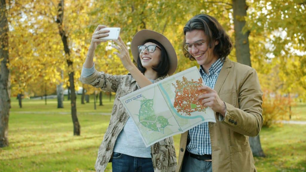 A couple taking a selfie with a map in a park.