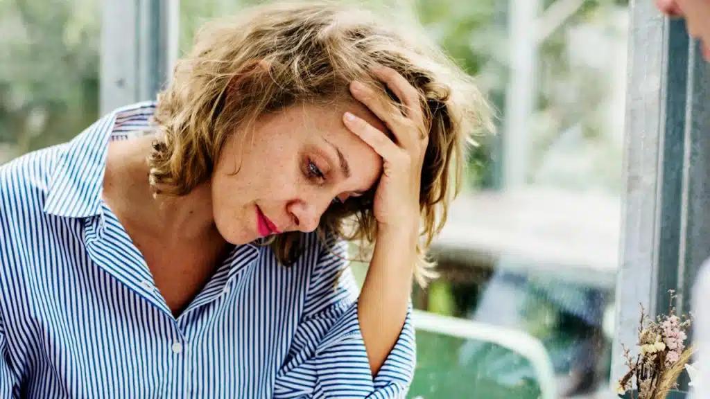 A distressed woman with her head in her hand.