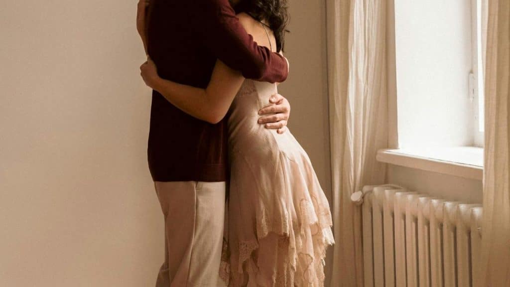 A couple embracing by a window indoors.