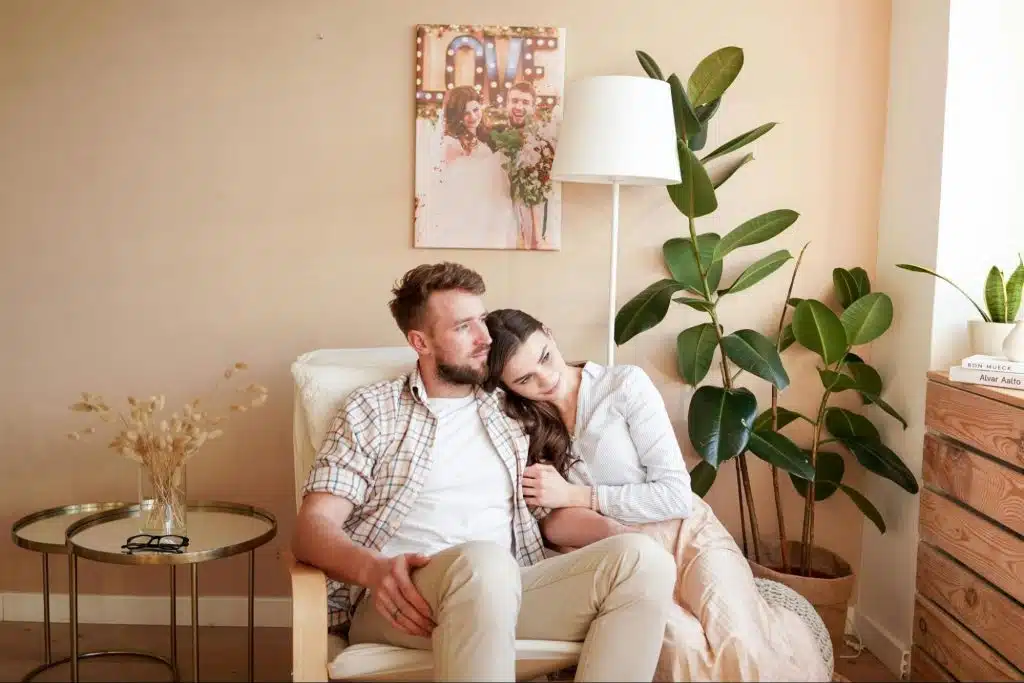 A woman leaning on a man’s shoulder as they sit on a couch and share a tender moment.