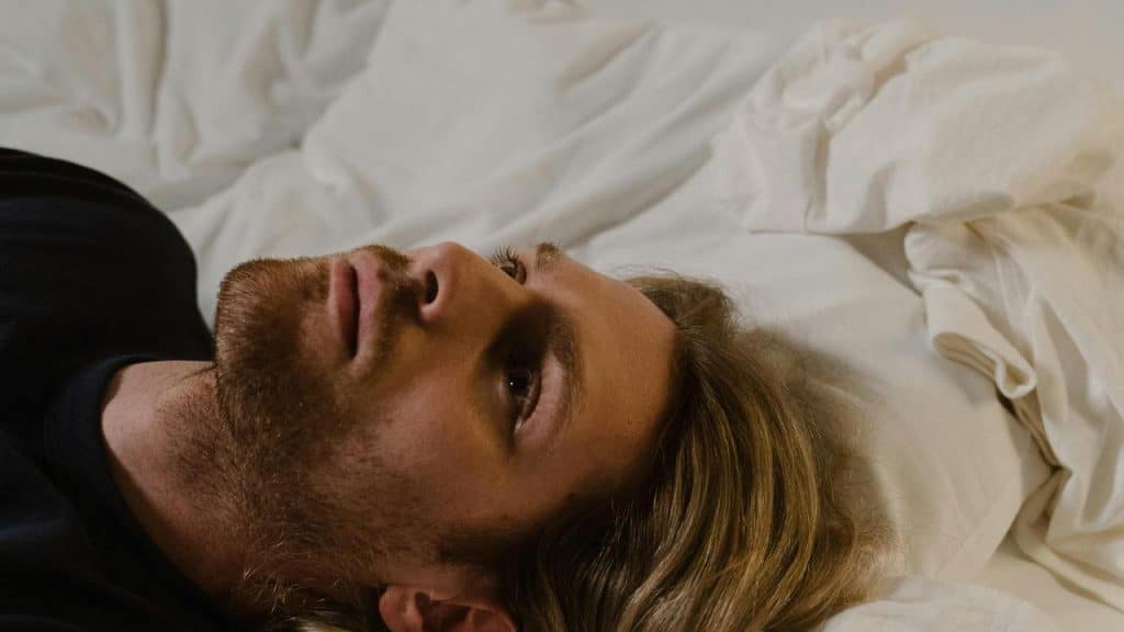 A man lying in bed staring upward.