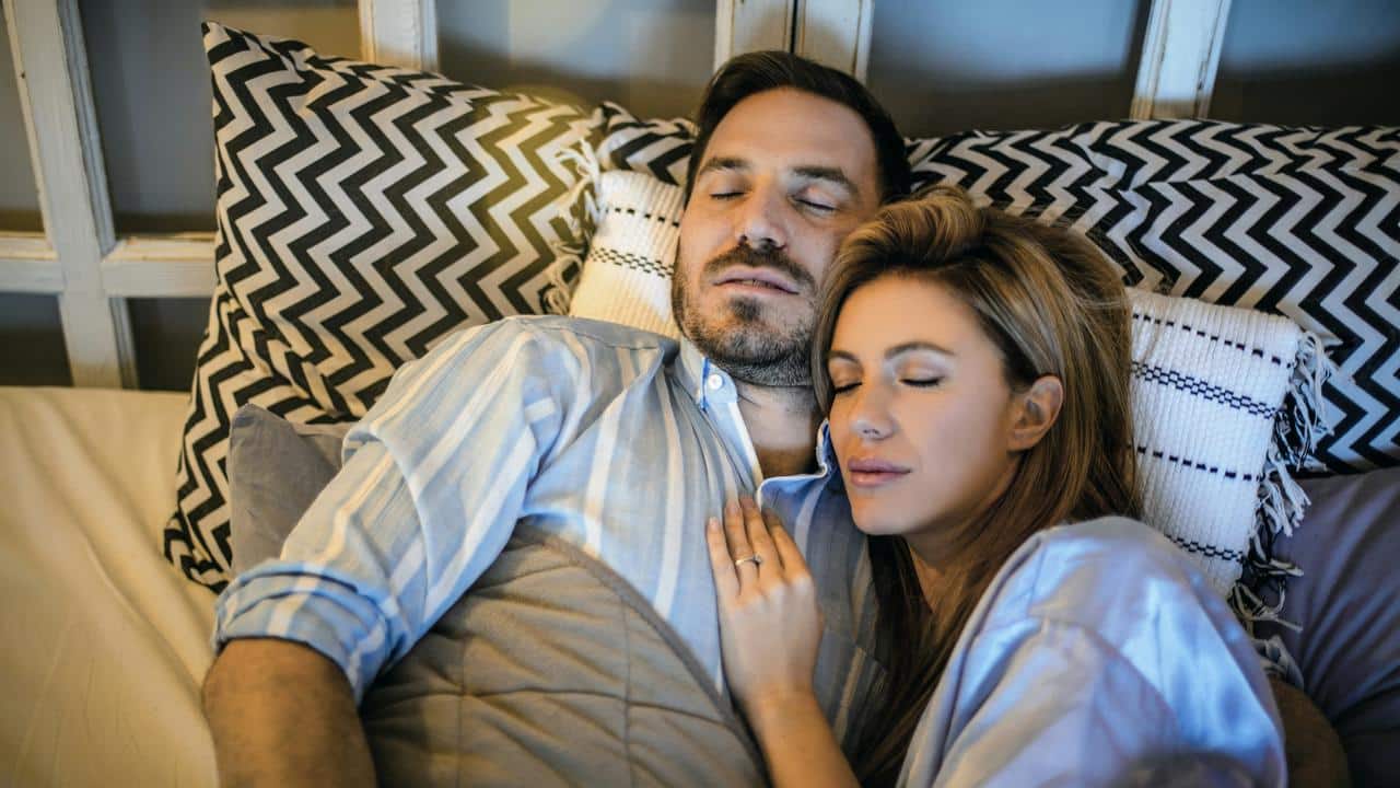 A couple peacefully sleeping together in bed.
