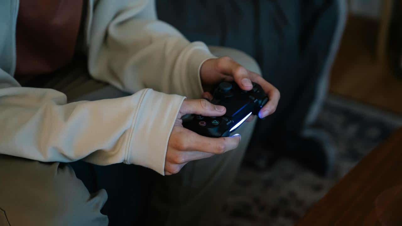 A person holding a video game controller while sitting indoors.