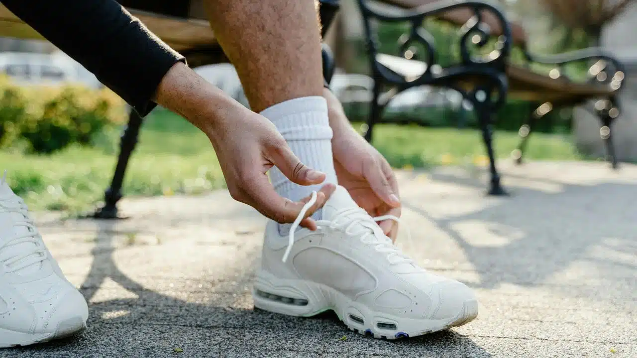 A person tying the laces of their running shoes outside.