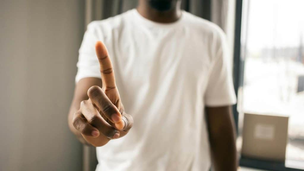A person holding up one finger indoors.