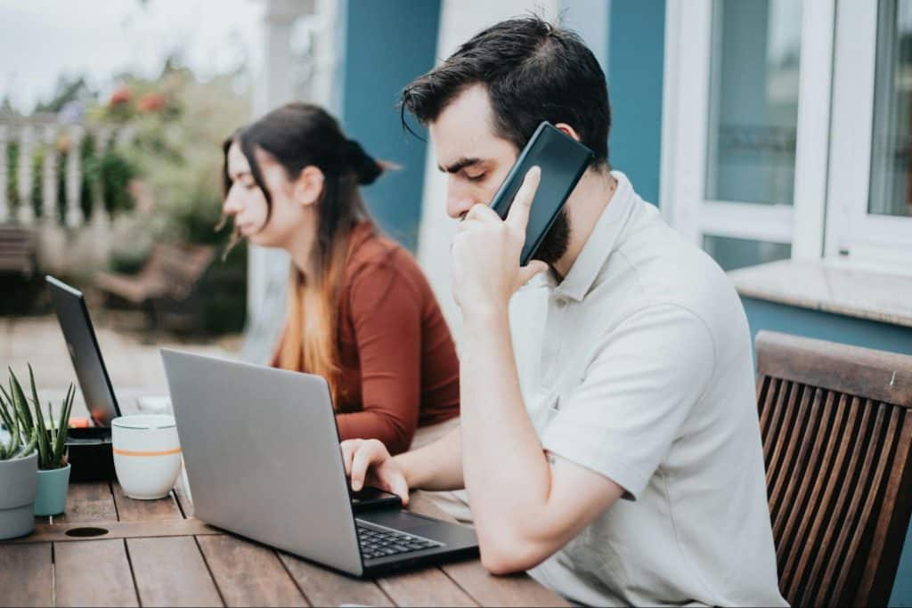 A man busy talking with someone on phone while a woman beside him