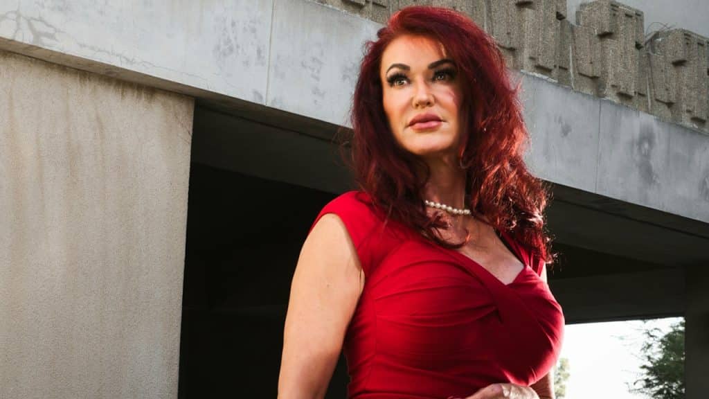 A woman in a red dress standing in front of a building.