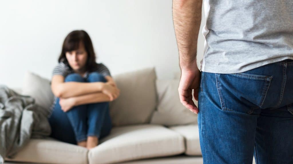A woman sitting on a couch in front of a man.