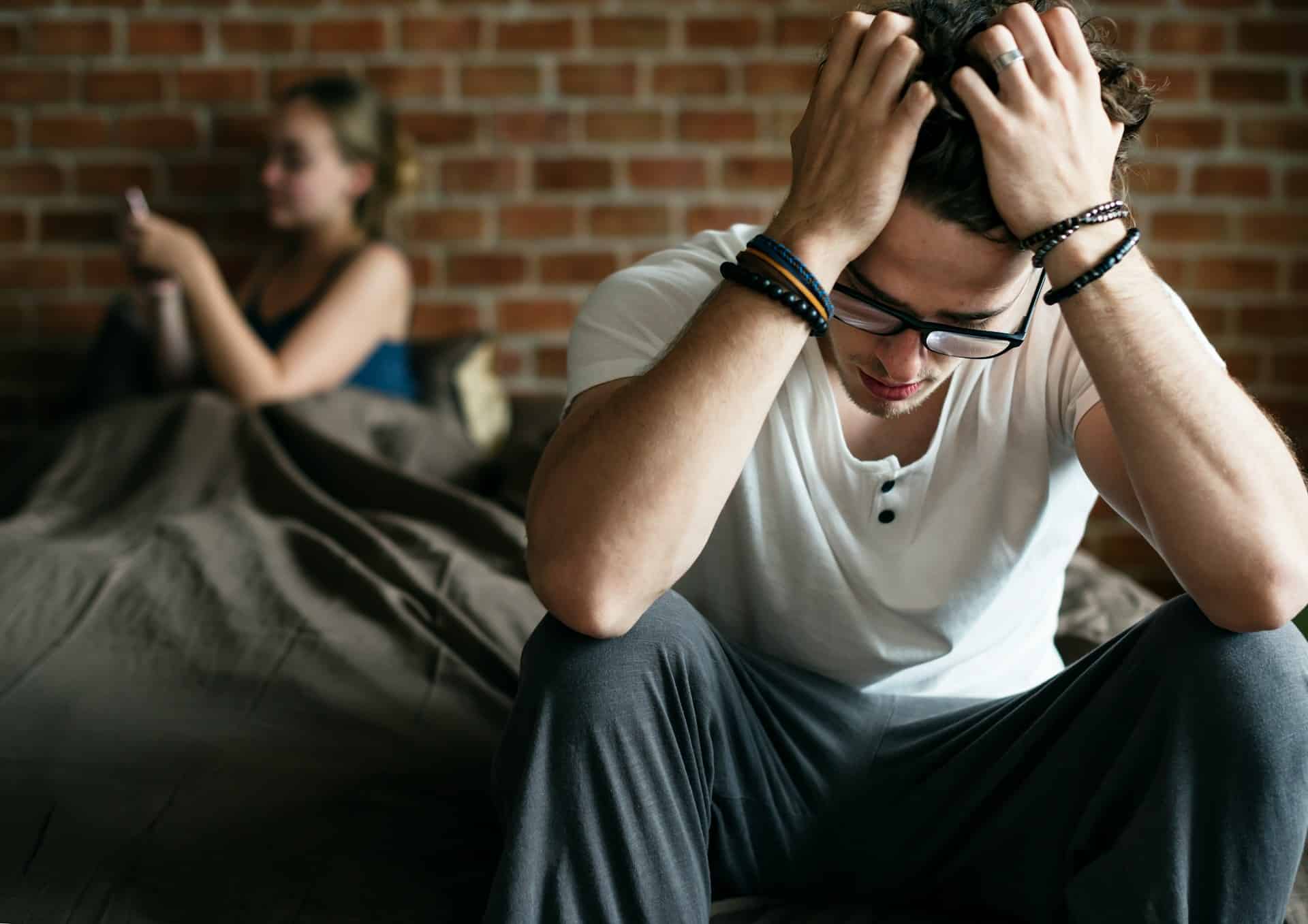 A frustrated man is sitting on the edge of the bed.