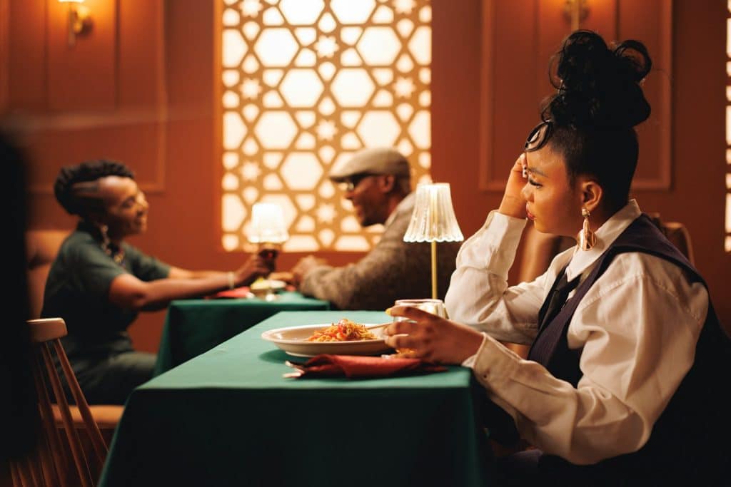 A woman looking at the couple sitting next to her table in a restaurant.