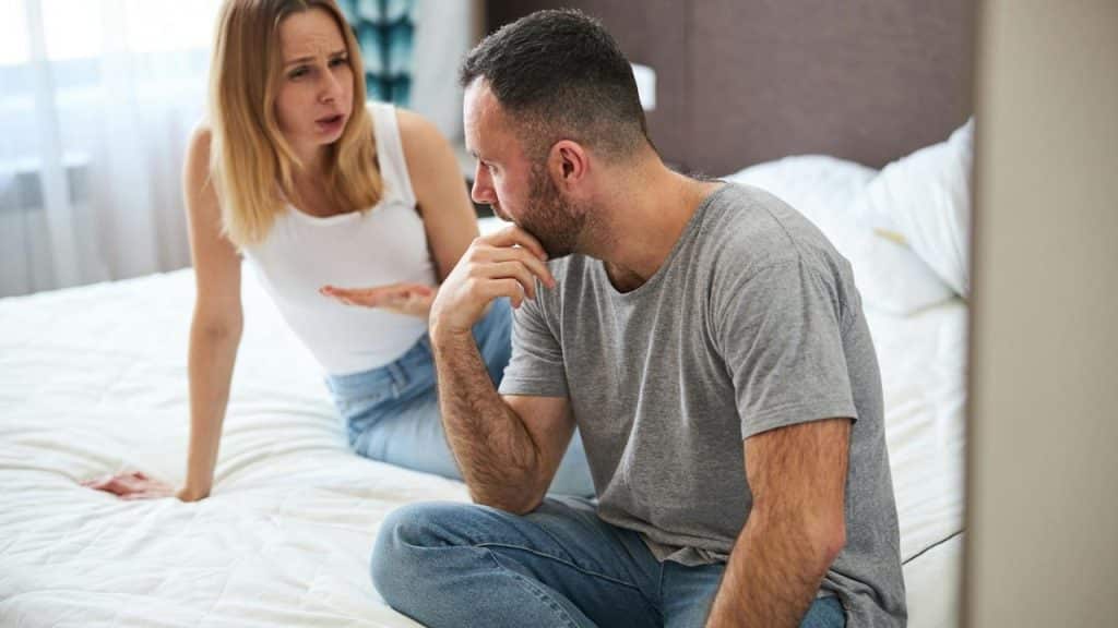 A displeased lady is talking to her husband while her husband touches his chin.
