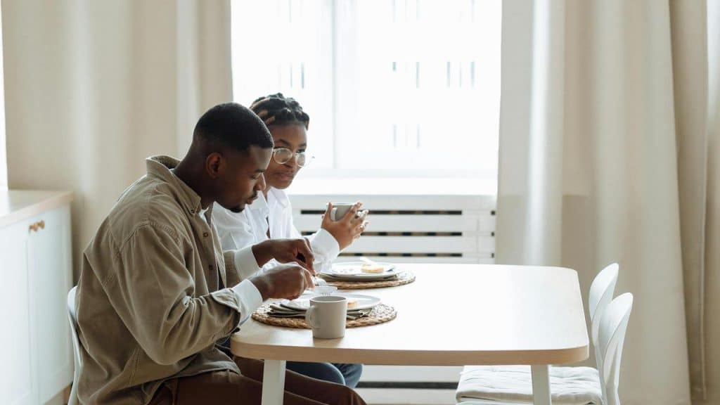 A couple eating breakfast together at a small kitchen table.