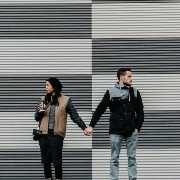A couple holding hands and looking in opposite directions.