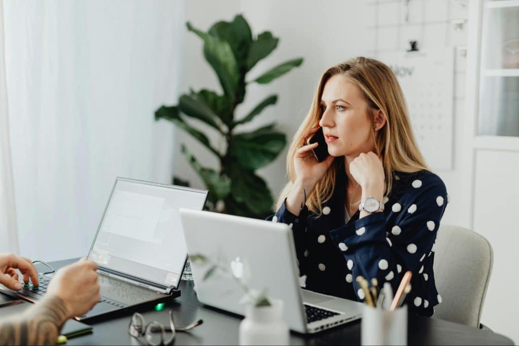 A woman speaking on phone in front of a man