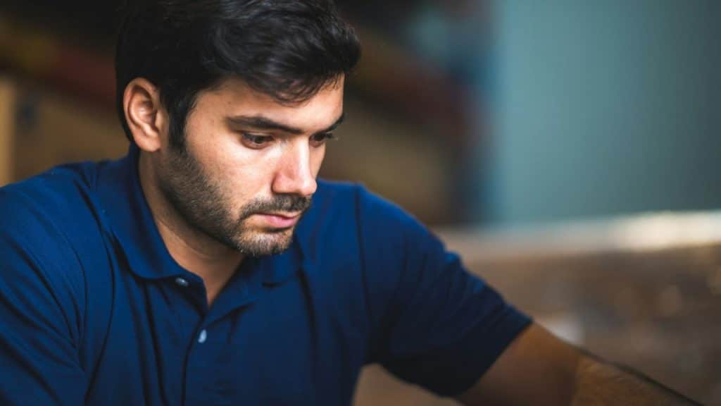 A man in a navy blue polo shirt looks down intently, concentrating on something.