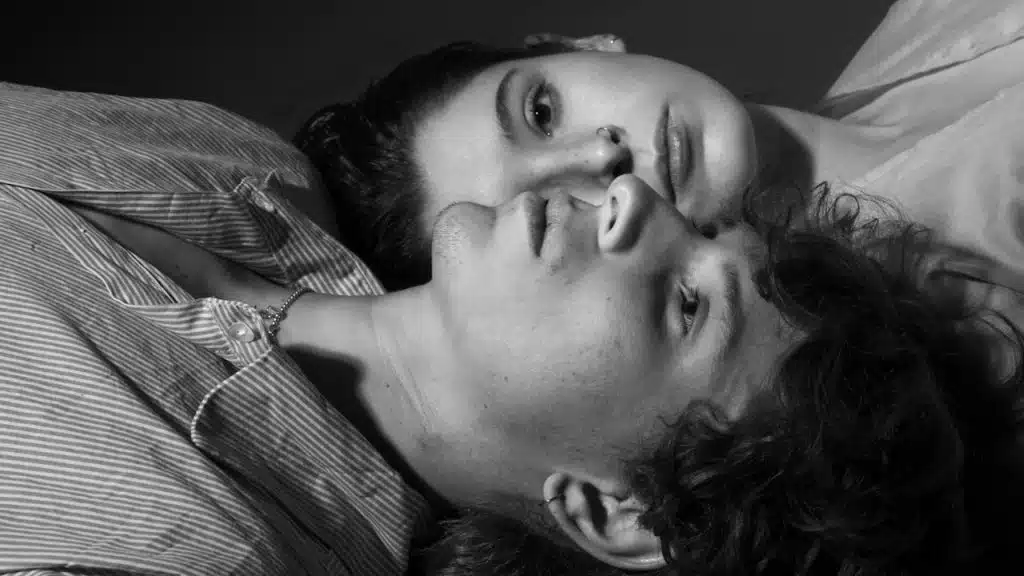A couple lying vertically opposite to each other with their heads touching.