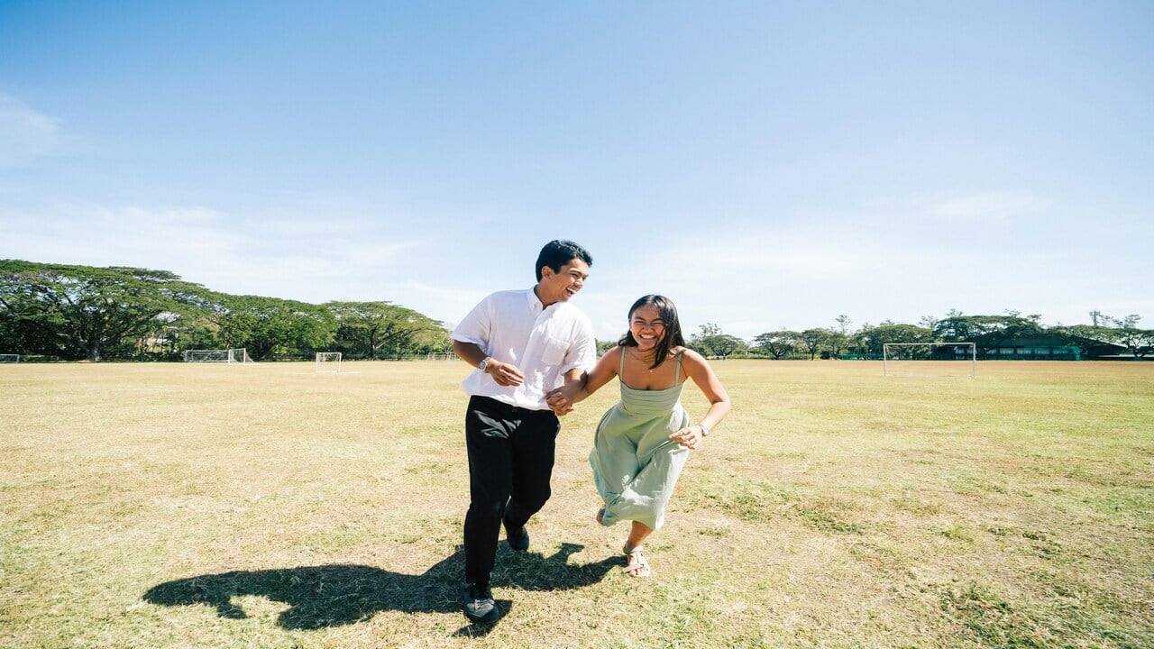 A happy couple running on a field