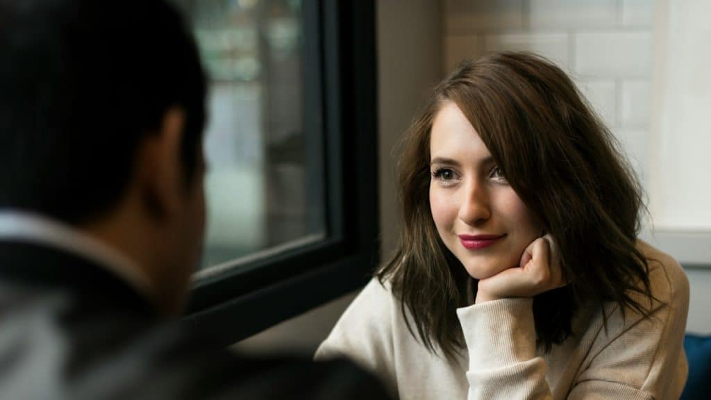 A beautiful woman looking at her boyfriend while sitting at a table.