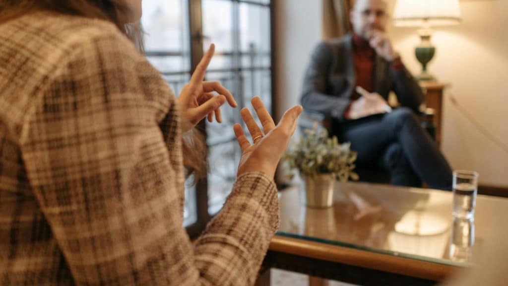 A person gesturing while talking to a seated listener.