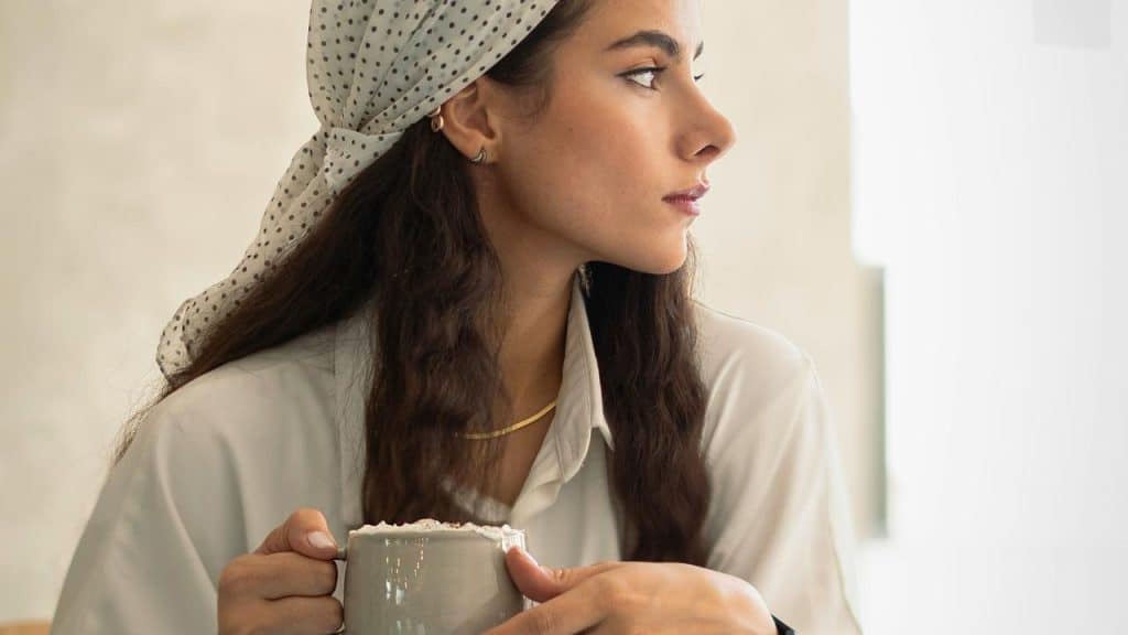 A woman holding a mug and looking to the side.