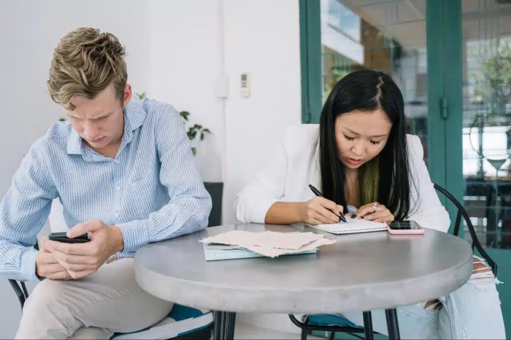 A man busy with his phone and a woman checking documents 