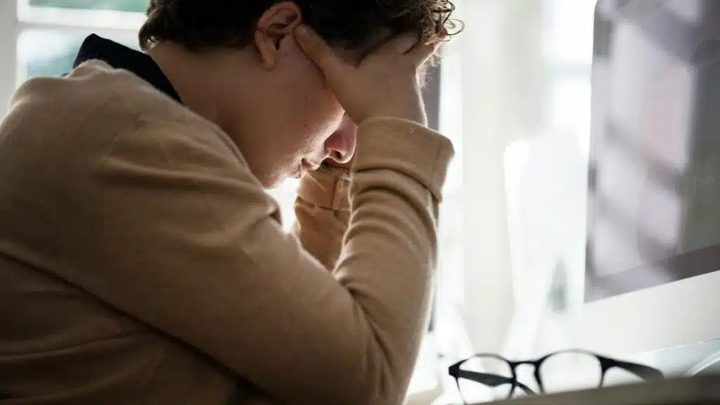 A person sitting at a desk holding their head in frustration or stress.