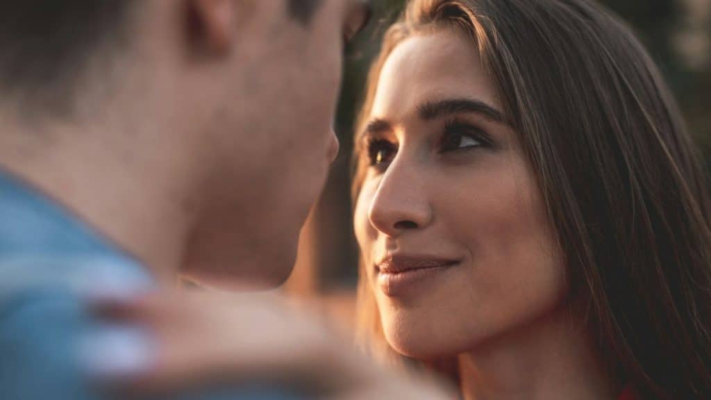 Close-up of a woman smiling, looking up at a man out of focus.