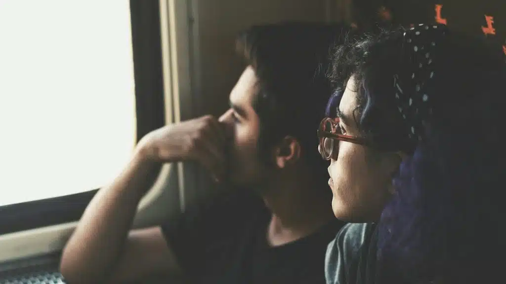 A man and a woman looking outside the window of the train.