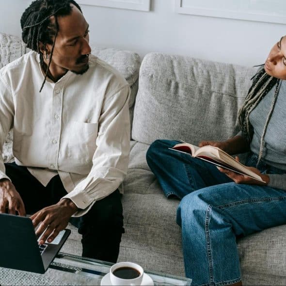 A man and woman at home sitting at the sofa
