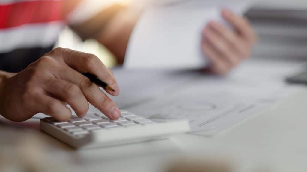 A person using a calculator while holding documents.
